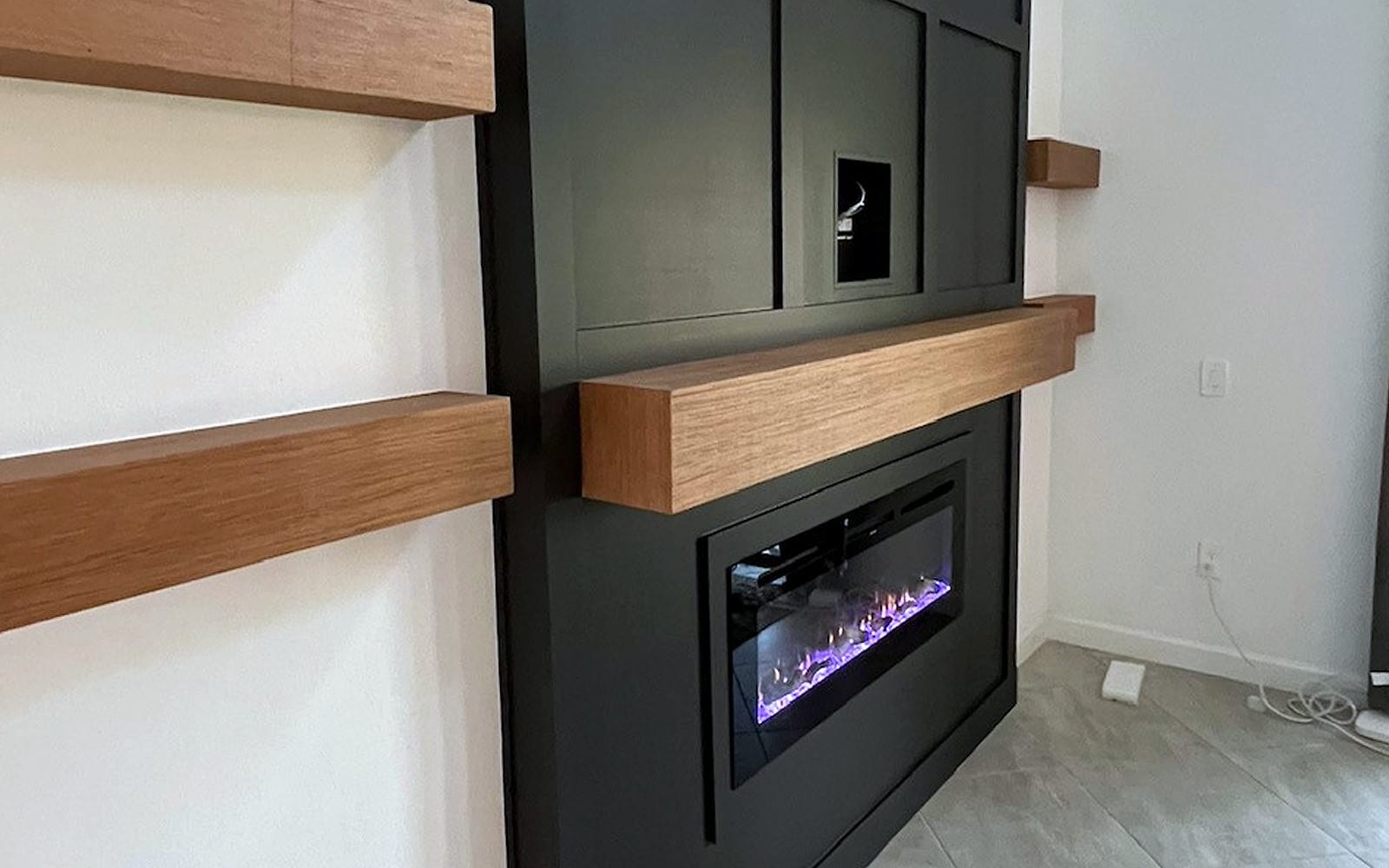 Black custom built-in with electric fireplace and floating wood mantel shelves